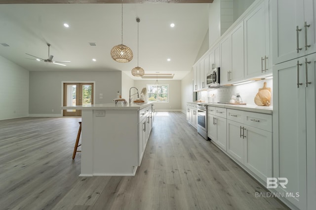 11341 Tall Timber Ln, Elberta, AL 36530 - kitchen with stainless steel microwave, healthy amount of natural light, lofted ceiling, a kitchen island with sink, and white cabinets