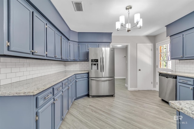 kitchen with light wood-style flooring, blue cabinets, visible vents, appliances with stainless steel finishes, and backsplash