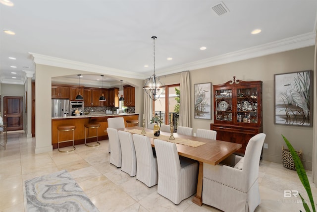 dining space with a notable chandelier, light tile patterned flooring, and crown molding