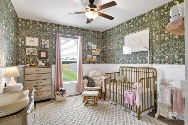 bedroom featuring ceiling fan, hardwood / wood-style flooring, and a nursery area