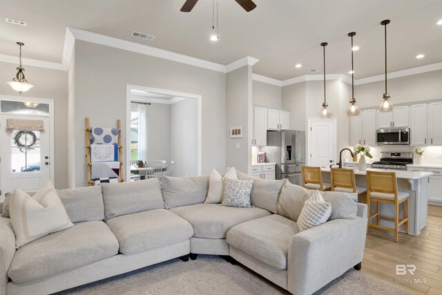 living room featuring ornamental molding, plenty of natural light, light hardwood / wood-style flooring, and ceiling fan