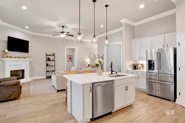 kitchen featuring white cabinets, stainless steel appliances, a kitchen island with sink, and sink