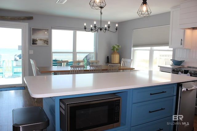 1757 W Beach Blvd, Gulf Shores, AL 36542 - kitchen with stainless steel microwave, blue cabinetry, light countertops, pendant lighting, and a chandelier