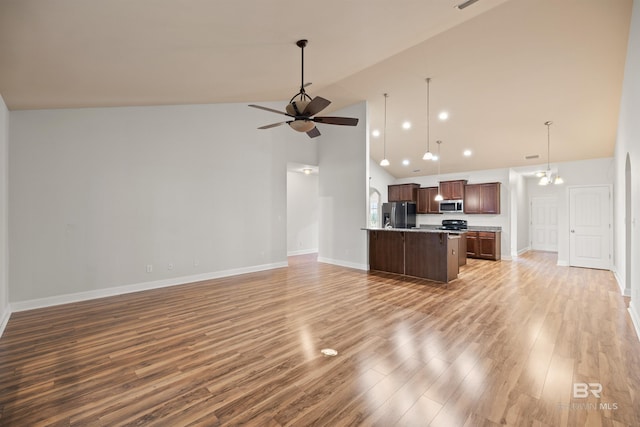 unfurnished living room with ceiling fan with notable chandelier, wood-type flooring, and high vaulted ceiling
