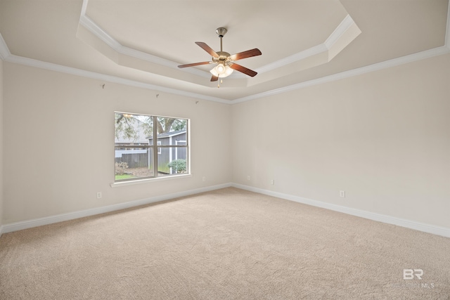 unfurnished room with a raised ceiling, ornamental molding, carpet, and ceiling fan