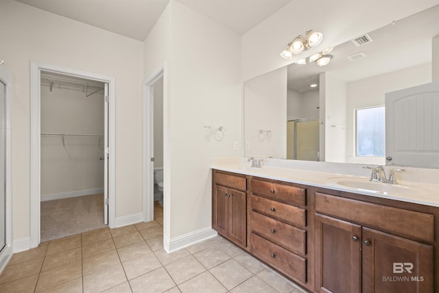bathroom with tile patterned floors, toilet, a shower with shower door, and vanity