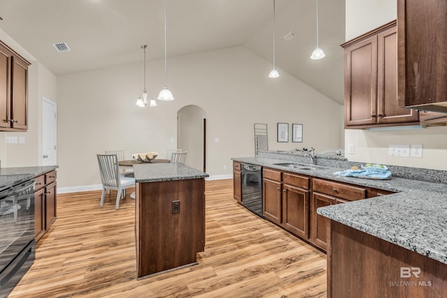 kitchen with sink, hanging light fixtures, a center island, black appliances, and stone countertops