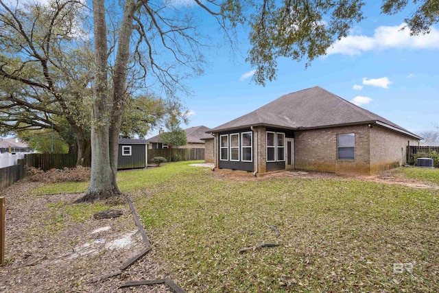 back of property with a lawn, central air condition unit, and a storage unit