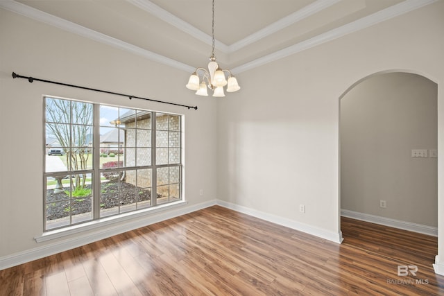 spare room featuring wood-type flooring, crown molding, a chandelier, and a tray ceiling