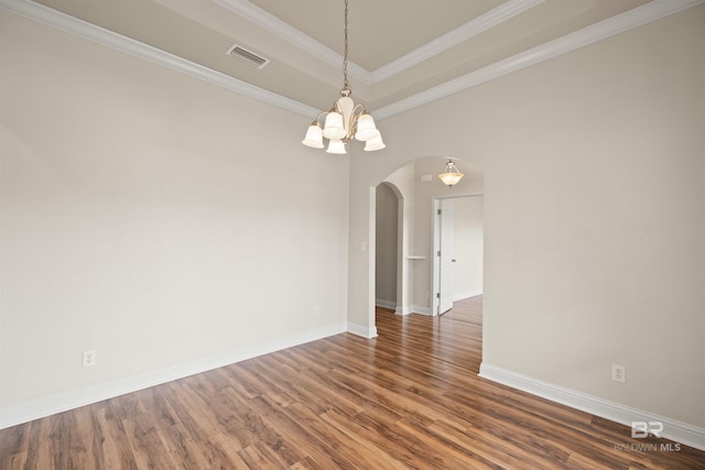 empty room with dark wood-type flooring, crown molding, and a raised ceiling