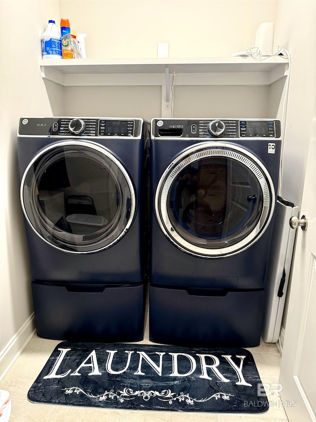 washroom featuring laundry area, washer and clothes dryer, tile patterned flooring, and baseboards