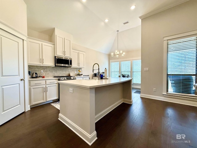 kitchen with light countertops, white cabinets, stainless steel microwave, and hanging light fixtures