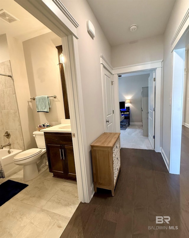 corridor with baseboards, visible vents, and wood finished floors