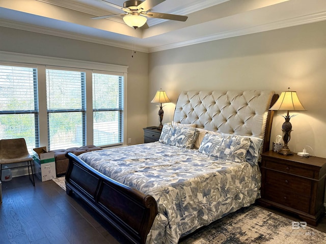 bedroom with a tray ceiling, ornamental molding, ceiling fan, and dark wood-type flooring