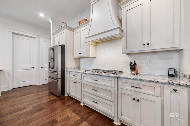 kitchen featuring custom exhaust hood, white cabinets, tasteful backsplash, and appliances with stainless steel finishes