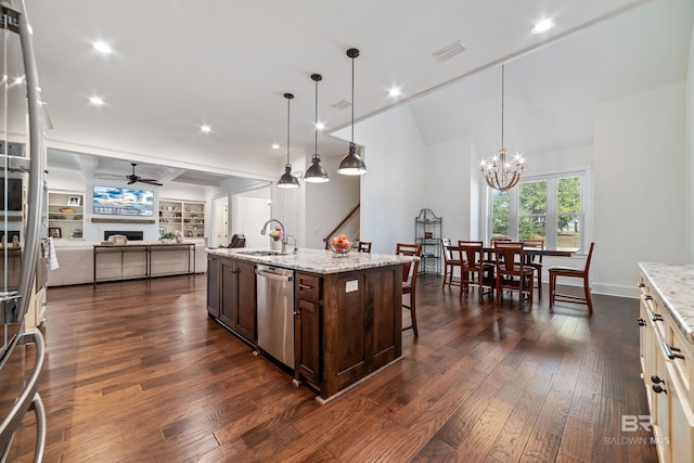 kitchen featuring a kitchen island with sink, stainless steel dishwasher, sink, pendant lighting, and light stone counters