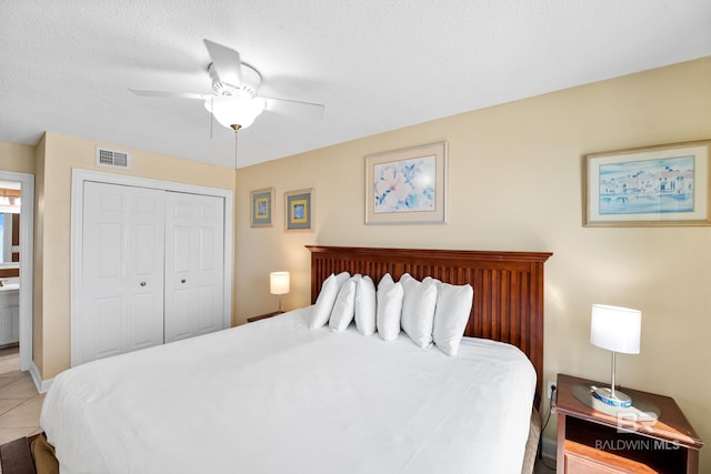 bedroom featuring visible vents, light tile patterned floors, a closet, a textured ceiling, and a ceiling fan