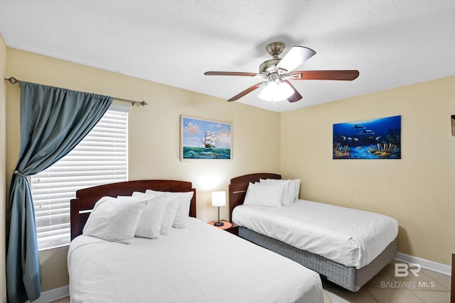 tiled bedroom featuring baseboards, a textured ceiling, and ceiling fan