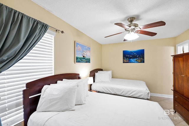 tiled bedroom featuring baseboards, multiple windows, a textured ceiling, and a ceiling fan