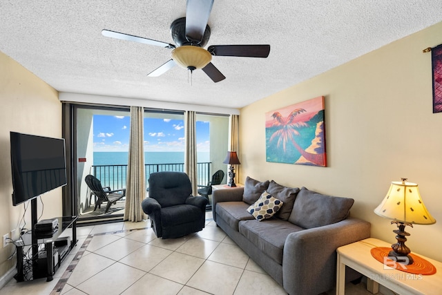 living room with light tile patterned flooring, a textured ceiling, ceiling fan, and a water view