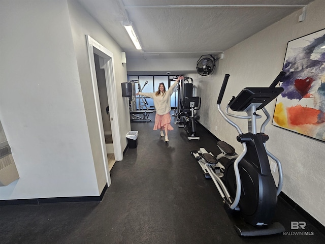 exercise area with a textured ceiling and baseboards