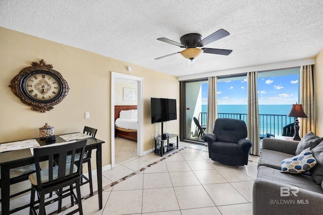 living room with light tile patterned floors, a ceiling fan, baseboards, and a textured ceiling