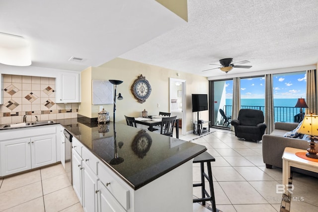 kitchen featuring tasteful backsplash, dishwasher, a breakfast bar, a peninsula, and a sink