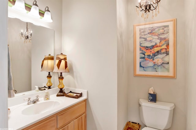 bathroom with toilet, a notable chandelier, and vanity