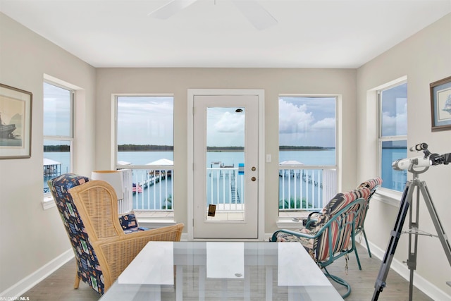 dining space featuring light hardwood / wood-style flooring, ceiling fan, a water view, and a wealth of natural light