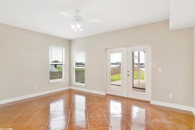 empty room featuring light tile flooring, ceiling fan, and french doors