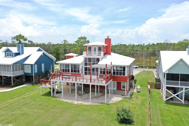 back of house with a wooden deck, a sunroom, and a lawn