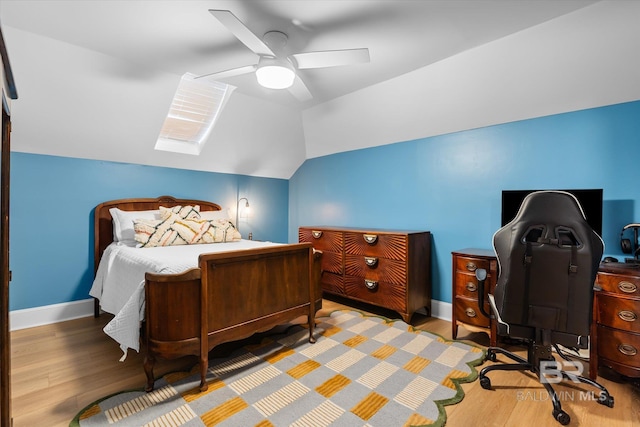 bedroom with hardwood / wood-style flooring, ceiling fan, and vaulted ceiling with skylight