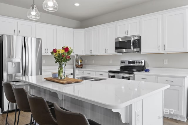 kitchen featuring stainless steel appliances, a kitchen island with sink, and hanging light fixtures