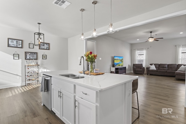 kitchen with sink, hanging light fixtures, stainless steel dishwasher, a kitchen island with sink, and white cabinets