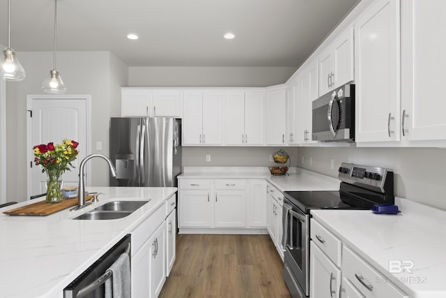 kitchen featuring pendant lighting, white cabinetry, sink, stainless steel appliances, and light stone countertops