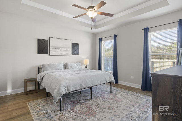 bedroom with crown molding, a tray ceiling, ceiling fan, and hardwood / wood-style flooring