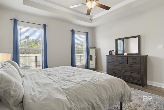 bedroom featuring crown molding, dark hardwood / wood-style floors, a raised ceiling, and multiple windows