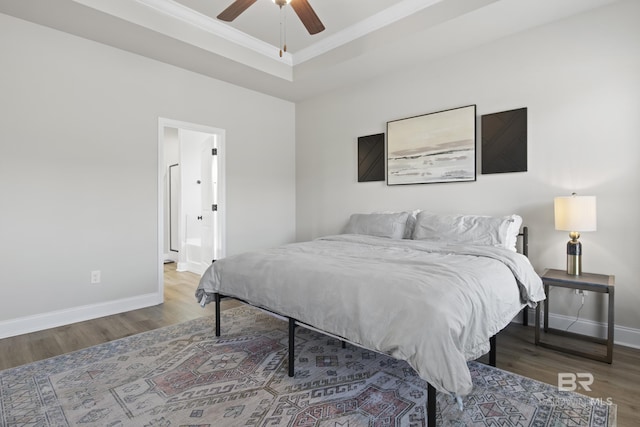 bedroom with crown molding, hardwood / wood-style floors, a tray ceiling, and ceiling fan