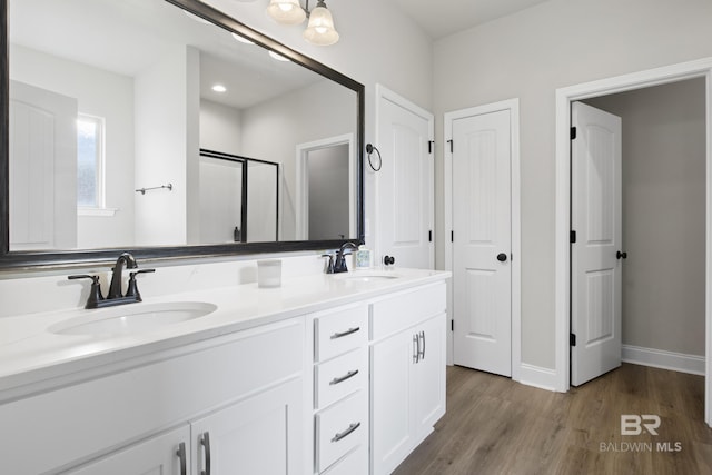 bathroom featuring wood-type flooring, a shower with shower door, and vanity