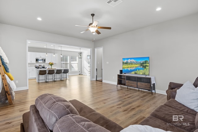 living room featuring light hardwood / wood-style flooring and ceiling fan