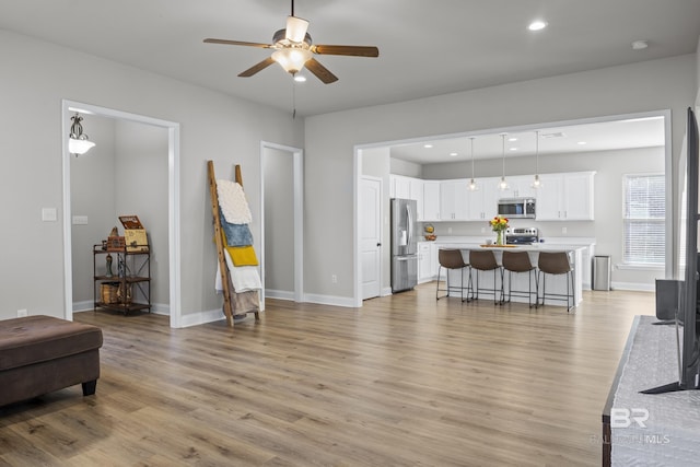 living room featuring ceiling fan and light hardwood / wood-style flooring