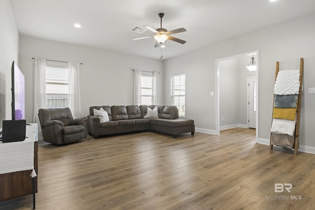 living room with a healthy amount of sunlight, dark wood-type flooring, and ceiling fan