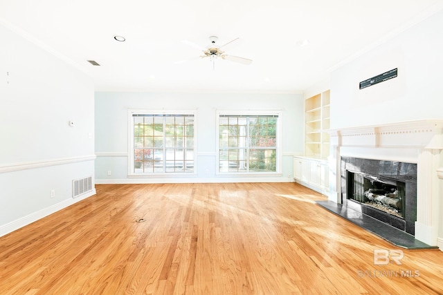 unfurnished living room featuring ornamental molding, built in features, ceiling fan, and light wood-type flooring