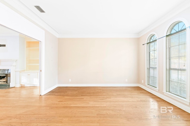 spare room featuring light hardwood / wood-style floors, ornamental molding, and a premium fireplace