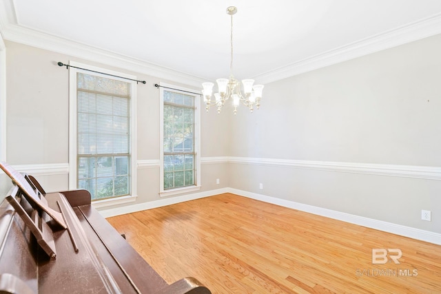 unfurnished room with a notable chandelier, hardwood / wood-style flooring, and ornamental molding