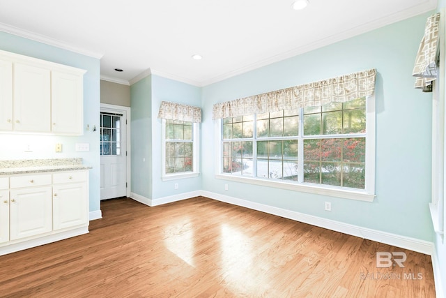 unfurnished dining area featuring ornamental molding and light wood-type flooring