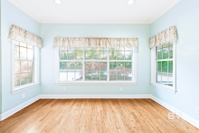 spare room featuring light hardwood / wood-style flooring, a wealth of natural light, and ornamental molding