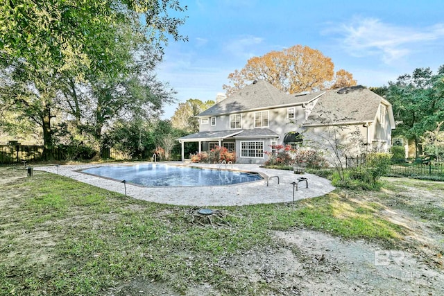 rear view of house featuring a fenced in pool, a lawn, and a patio