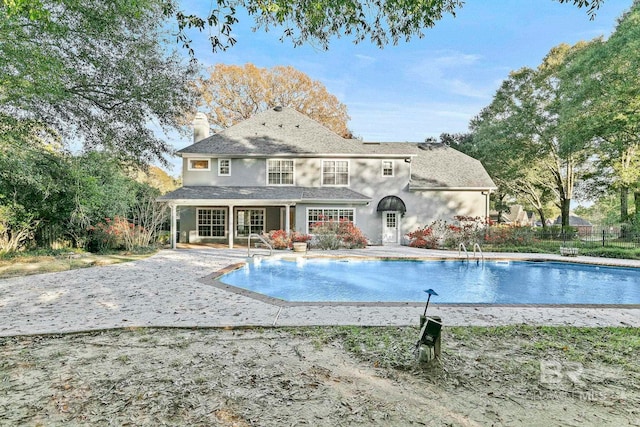 rear view of property with a fenced in pool and a patio area