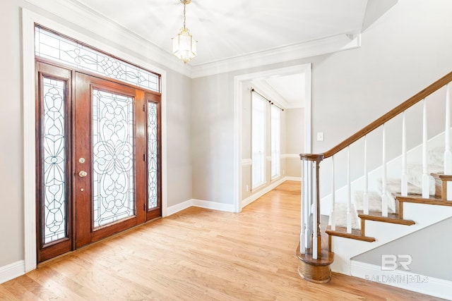 entrance foyer with a notable chandelier, a wealth of natural light, ornamental molding, and light wood-type flooring